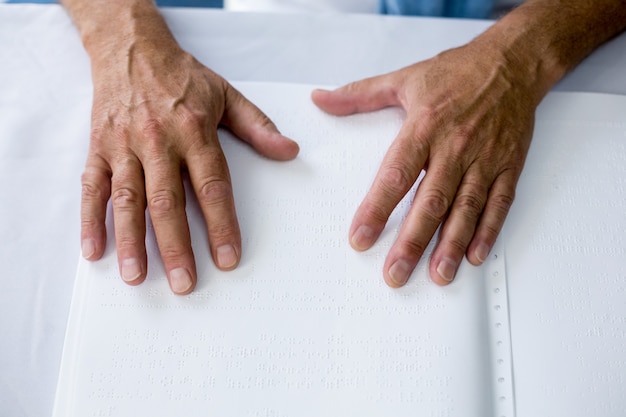 Foto senior usando braille para leer