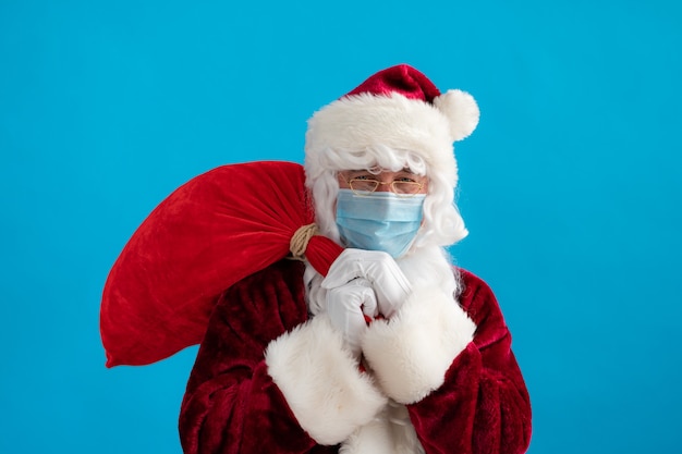 Sênior vestindo fantasia de Papai Noel e máscara protetora. Homem segurando a sacola com presentes. Feriado de Natal durante a pandemia de coronavírus COVID 19 conceito