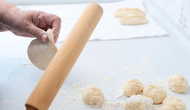 Foto senior woman hands making pies mit apfelfüllung auf einem weißen küchentisch mit hölzernem nudelholz im hintergrund selektiver fokus kochen zu hause konzept tradition hausgemachtes essen