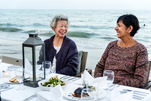 Senioren, die ein Abendessen am Strand haben