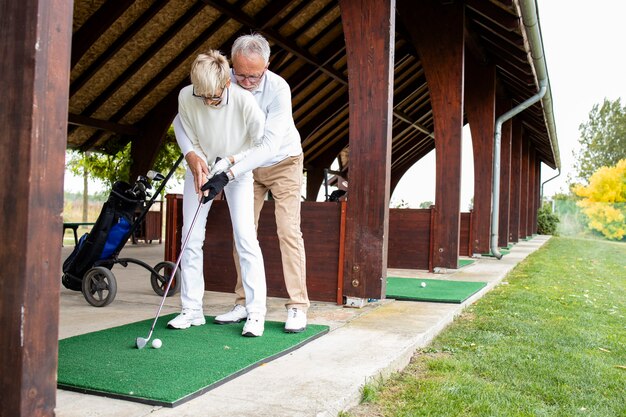 Senioren im Ruhestand lernen Golf auf dem Golfplatz zu spielen.