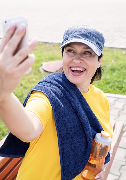 Foto senioren im sport, aktive senioren lächeln, seniorsportlerin macht ein selfie im freien im park