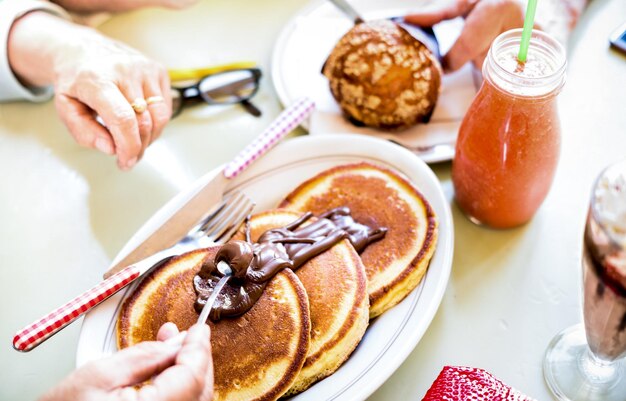 Seniorenpaar isst Pfannkuchen mit Schokolade an der Kaffeebar