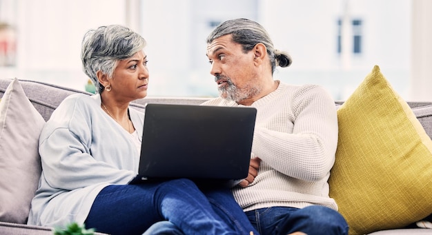 Seniorenpaar Laptop und ernsthafte Diskussion auf dem Sofa für finanzielle Planung Budget oder Schulden zu Hause Ältere Mann und Frau sprechen mit dem Computer für Finanzen Hypothek Darlehen oder Krise im Wohnzimmer