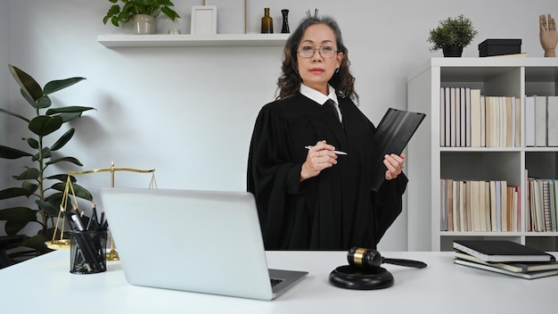 Seniorin in Robenuniform, die ein Dokument hält und selbstbewusst in die Kamera blickt Anwalt für Justiz und Recht Anwaltskonzept