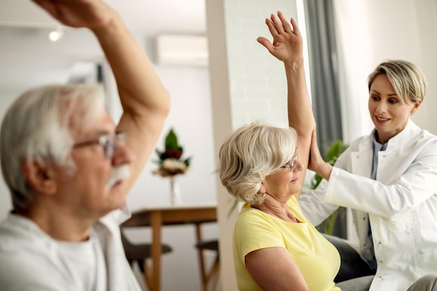 Seniorin und ihr Mann trainieren zu Hause mit Physiotherapeuten