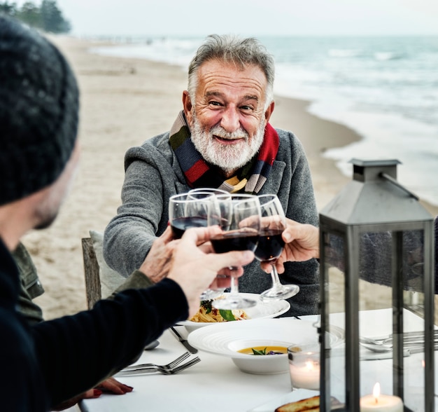 Seniors brindando con vino tinto en la playa