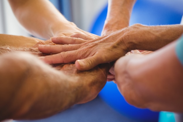 Seniors e instructor de fitness juntando sus manos