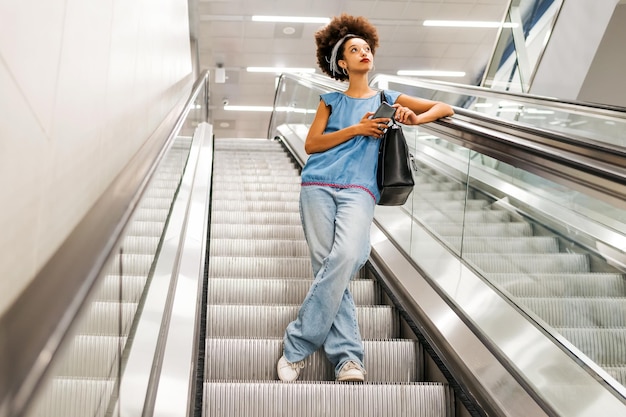 Señora afroamericana en escaleras mecánicas del metro