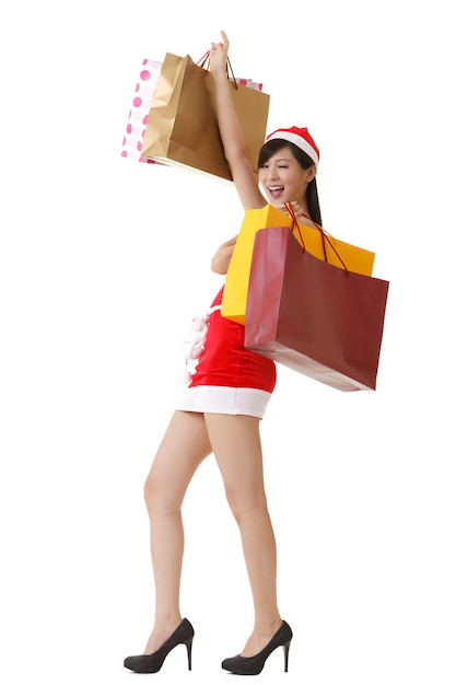 Señora alegre de Navidad sosteniendo bolsas de la compra y sonriente, retrato de cuerpo entero aislado sobre fondo blanco.