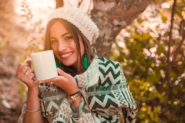 Señora alegre con taza en el bosque