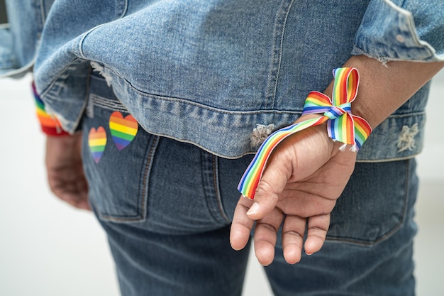 Señora asiática con pulseras de la bandera del arco iris, símbolo del mes del orgullo LGBT, celebra anualmente en junio social de derechos humanos gay, lesbiana, bisexual y transgénero