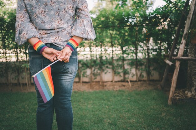 Señora asiática que sostiene la bandera del color del arco iris, símbolo del mes del orgullo LGBT, celebra anualmente en junio las redes sociales de gays, lesbianas, bisexuales, transgénero, derechos humanos.