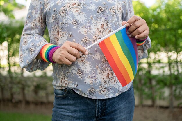 Señora asiática que sostiene la bandera del color del arco iris, símbolo del mes del orgullo LGBT, celebra anualmente en junio las redes sociales de gays, lesbianas, bisexuales, transgénero, derechos humanos.