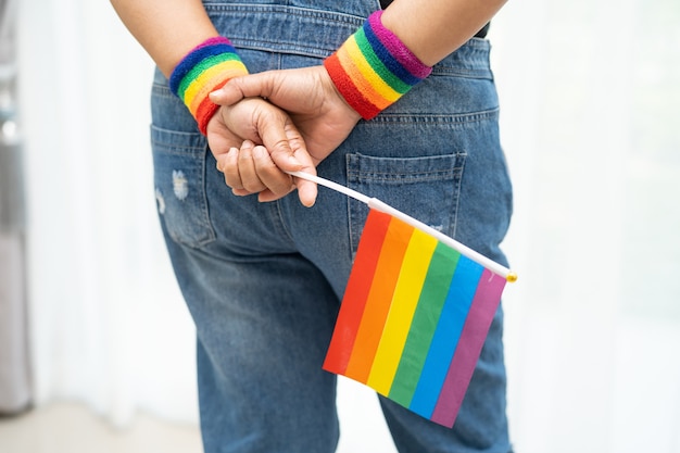 Señora asiática sosteniendo el símbolo de la bandera del color del arco iris del mes del orgullo lgbt