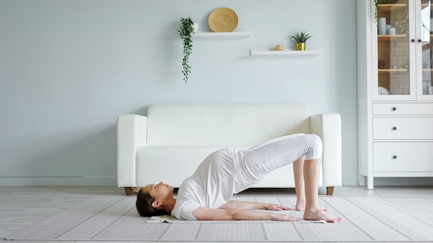 Señora bastante embarazada hace ejercicios practicando yoga en casa