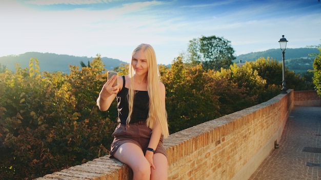 Señora bonita haciendo selfie en smartphone frente a la hermosa naturaleza del paisaje