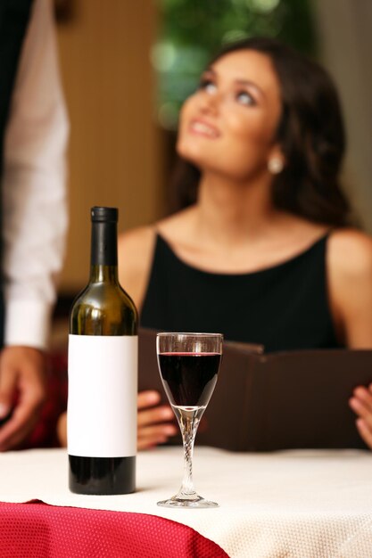 Señora bonita joven en el restaurante. El mesero toma el menú