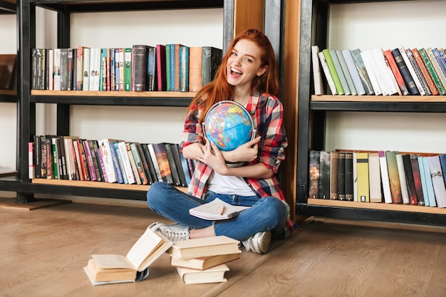 Señora bonita pelirroja joven feliz en biblioteca