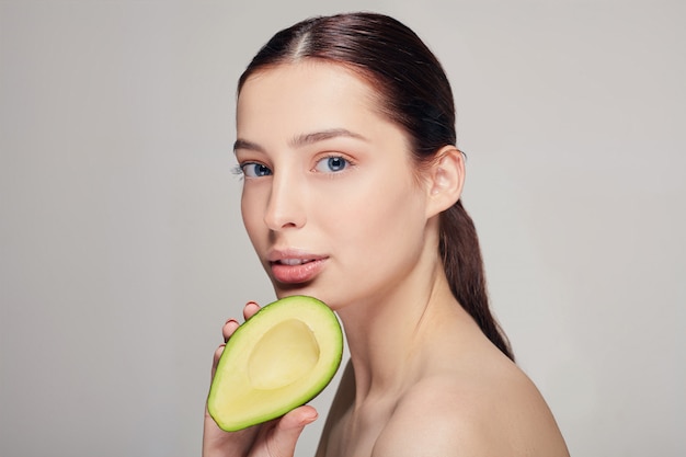 Señora de cabello castaño con aguacate en la mano