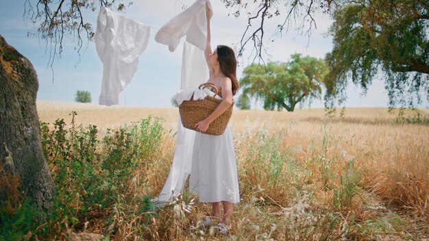 Foto una señora de campo tomando lino de la cuerda en el campo de verano una mujer puso la ropa en la canasta