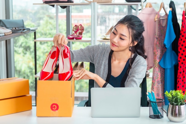 Señora casual asiática feliz trabajando emprendedor pequeña empresa PYME en tienda de ropa.