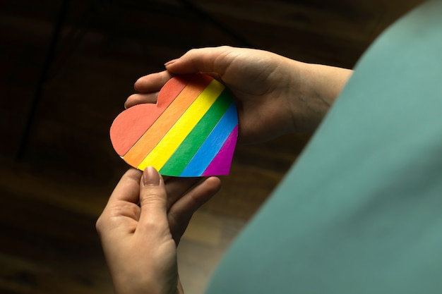 Señora caucásica sosteniendo la bandera del color del arco iris en forma de corazón, símbolo del mes del orgullo LGBT celebrar, comunidad de gays, lesbianas, bisexuales y transgénero, concepto de derechos humanos