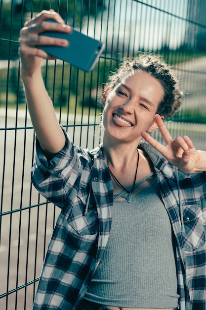 Foto señora emocional alegre sonriendo y mostrando su lengua mientras toma selfies divertidos