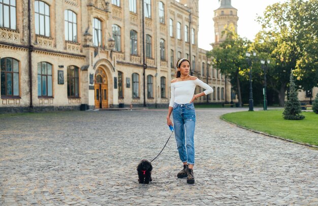 señora se encuentra en la calle de un hermoso casco antiguo con un perro con correa y mira hacia otro lado