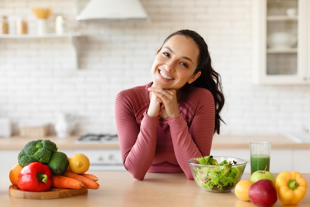 Foto señora especialista en nutrición posando en la mesa de la cocina con verduras en el interior