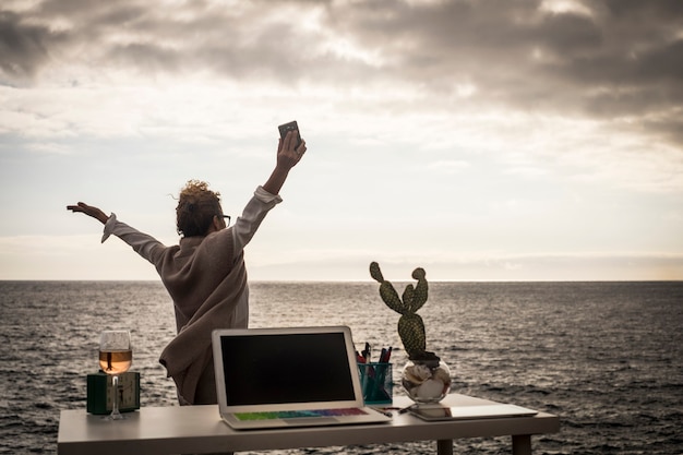 Señora feliz trabajando al aire libre cerca del océano en una oficina libre alternativa sin paredes y límites