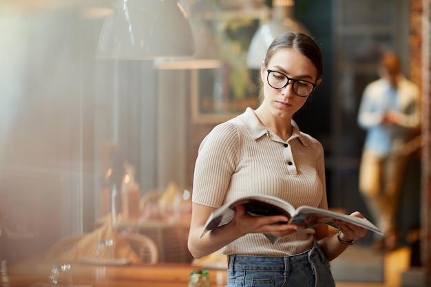 Señora inteligente leyendo una revista en el café