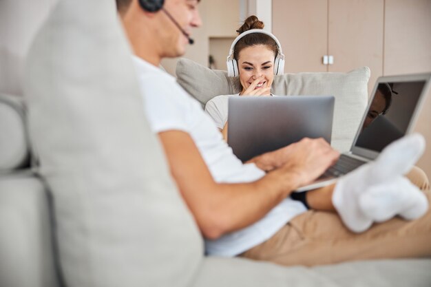 Señora joven atractiva que trabaja en la computadora portátil al lado de su novio