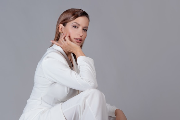 Señora joven con estilo en un traje de pantalón blanco, retrato en el estudio.