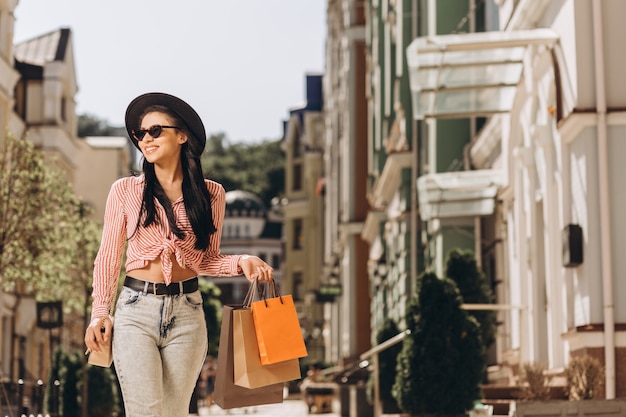 Señora joven feliz en un día soleado en la calle con bolsas de la compra. Banner del sitio web