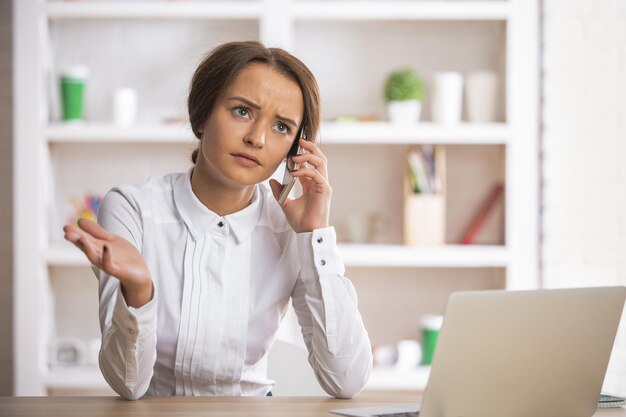 Señora en el lugar de trabajo hablando por teléfono inteligente