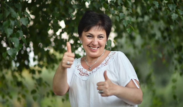 Señora madura disfrutando del verano al aire libre con los pulgares para arriba