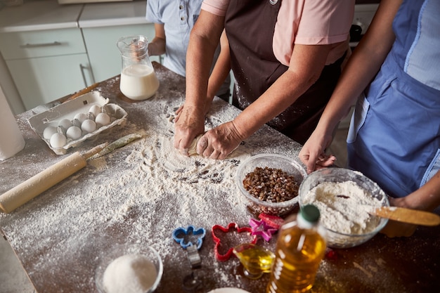 Señora mayor preparando la masa para hornear con sus hijos