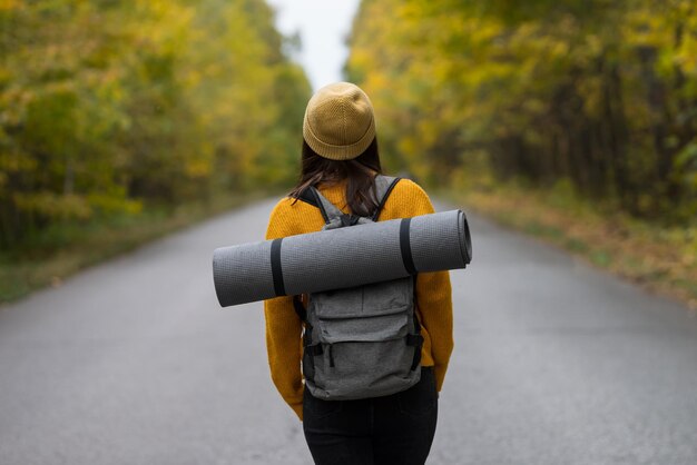 Señora con mochila de viaje disfruta de la atmósfera del camino forestal