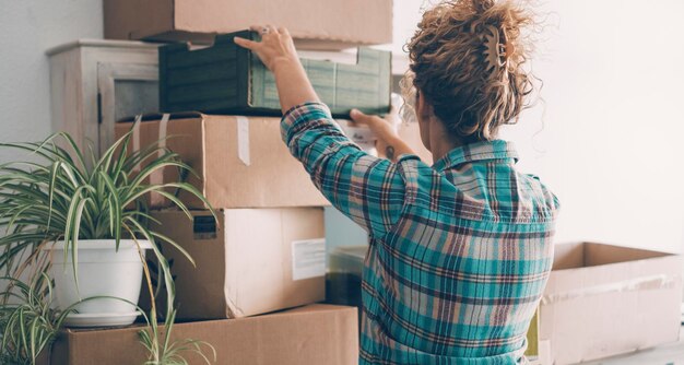 Una señora mudándose de casa y trabajando con una caja de cartón contra una pared Concepto de nueva vida aventura independencia mujeres personas reubicándose Hipoteca bancaria gente real nuevo propietario casa apartamento