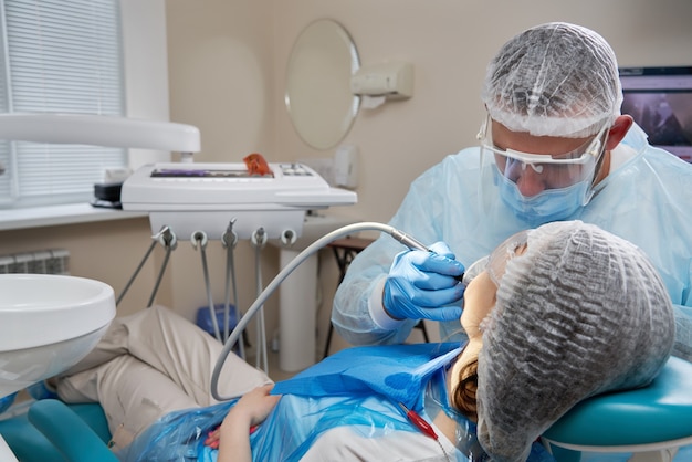 Señora paciente sentada en la silla de estomatología, diente de perforación del dentista, clínica moderna