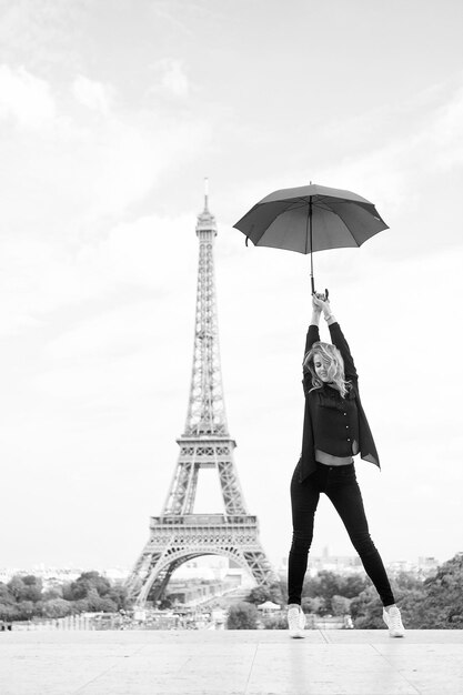 Señora con paraguas posando frente al fondo del cielo de la Torre Eiffel Señora turista paseos deportivos y activos en el centro de la ciudad de París con paraguas Chica turista disfruta de paseos y turismo Concepto de viaje