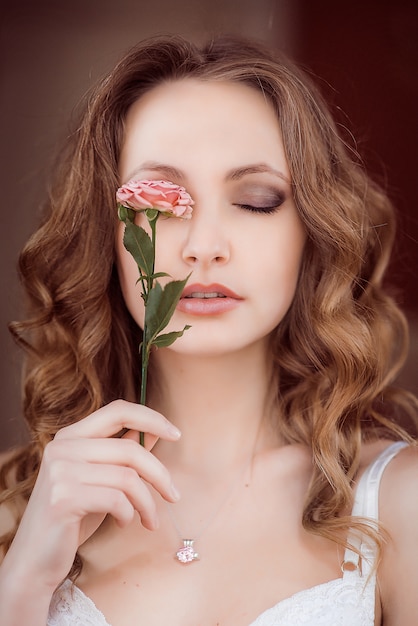 Señora con el pelo rizado sostiene la rosa rosada antes de sus ojos