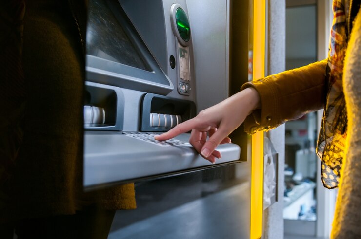 Señora que usa el cajero automático para retirar su dinero.