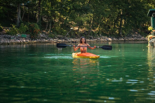 Foto señora remando el kayak en el lago tranquilo