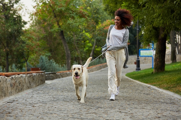 Señora sana divertida corriendo por la mañana con su perro en el parque