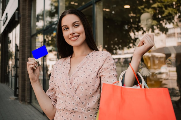 Foto señora sostenga muchas bolsas y tarjeta de crédito después de comprar