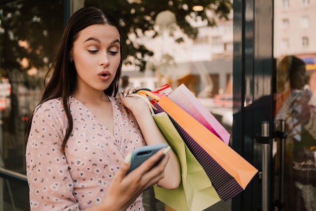 Foto señora sostenga muchas bolsas y teléfono después de ir de compras