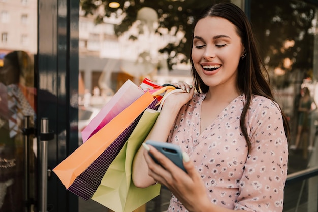 Señora sostenga muchas bolsas y teléfono después de ir de compras