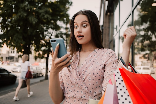 Señora sostenga muchas bolsas y teléfono después de ir de compras